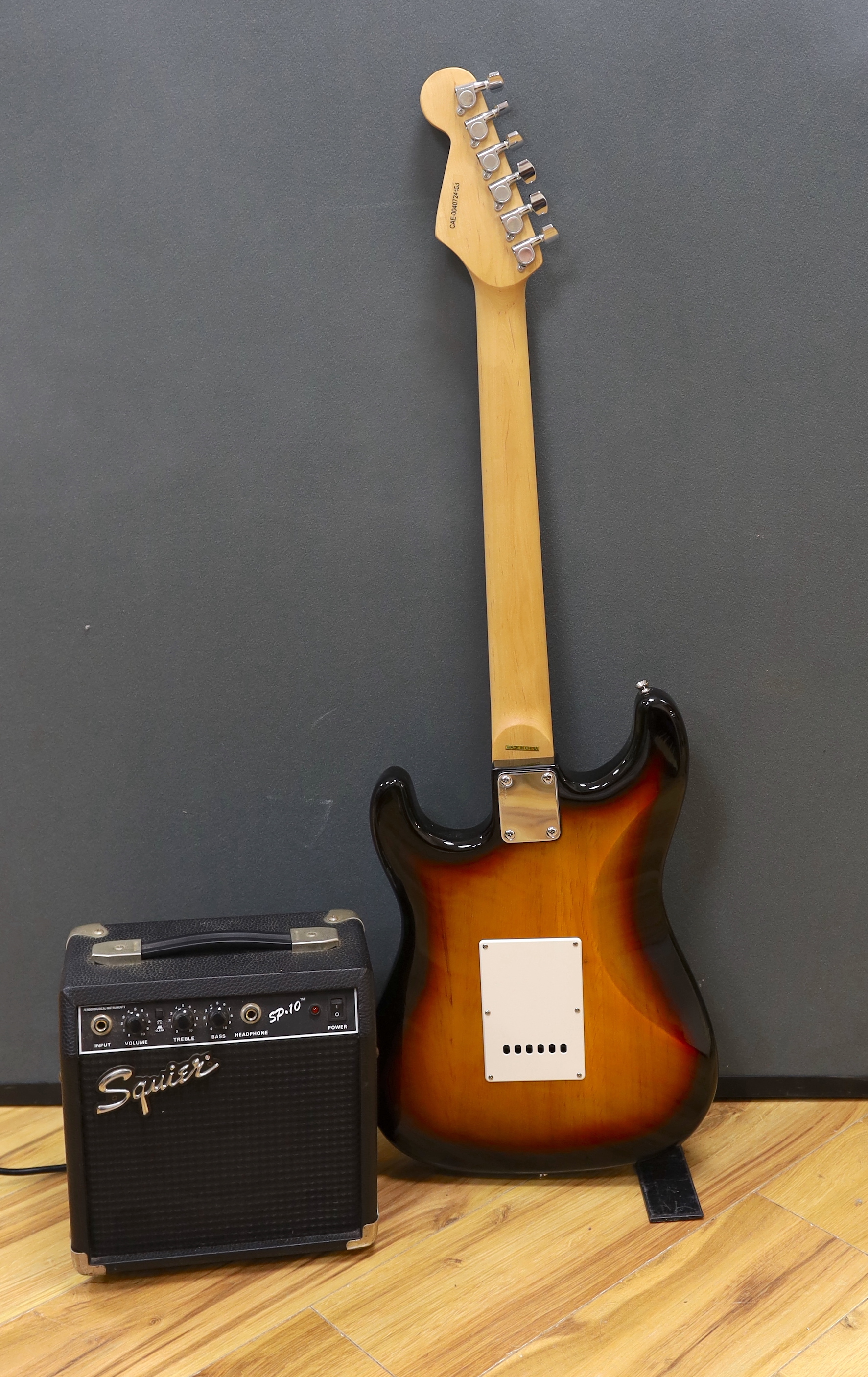 A Squier Strat by Fender Sunburst electric guitar made in China with rosewood neck, together with a small Squire SP-10 amp